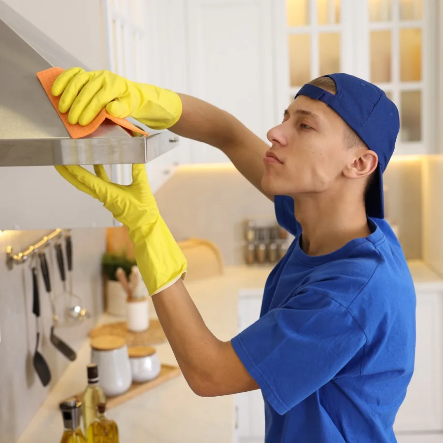 Cleaner detailing a kitchen rangehood during a vacate clean